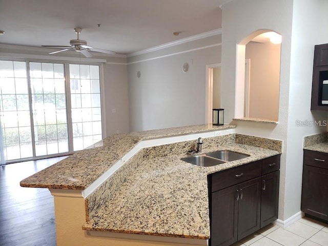 kitchen featuring sink, ceiling fan, light stone counters, ornamental molding, and kitchen peninsula