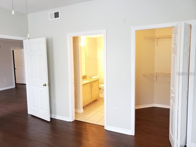 unfurnished bedroom featuring a walk in closet, dark hardwood / wood-style floors, connected bathroom, and a closet