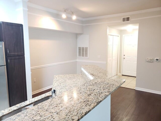 kitchen featuring sink, stainless steel refrigerator, ornamental molding, light stone countertops, and light hardwood / wood-style floors