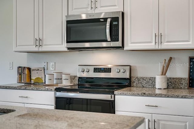 kitchen with appliances with stainless steel finishes, white cabinets, and light stone counters