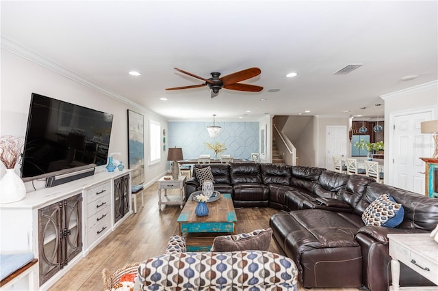 living area featuring an accent wall, ornamental molding, recessed lighting, and light wood-style floors