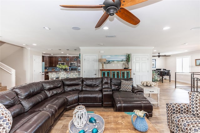 living room featuring ornamental molding, light wood-type flooring, visible vents, and recessed lighting