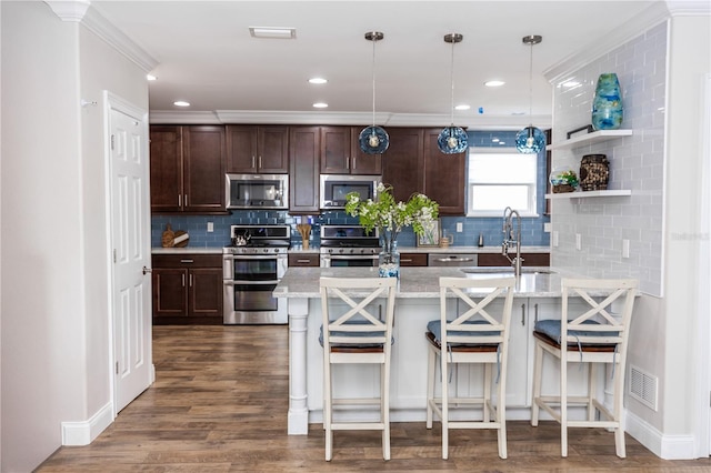 kitchen featuring a kitchen bar, stainless steel appliances, a sink, and decorative light fixtures