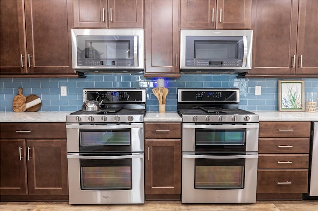 kitchen featuring dark brown cabinets, appliances with stainless steel finishes, backsplash, and light stone counters