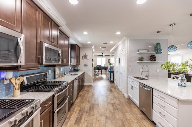 kitchen with appliances with stainless steel finishes, crown molding, a sink, and open shelves