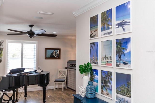 living area with a ceiling fan, crown molding, baseboards, and wood finished floors