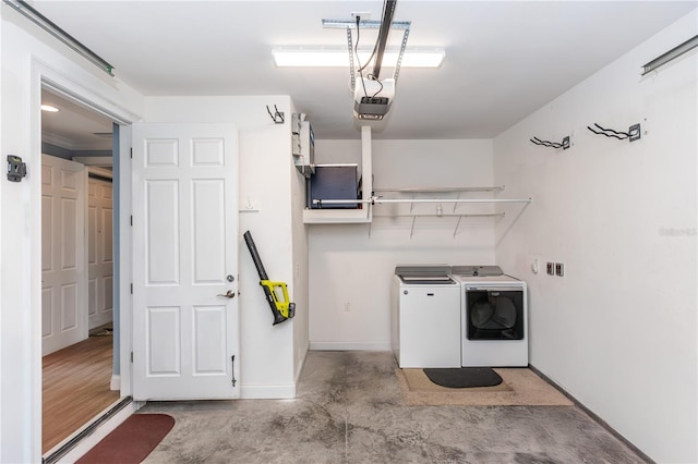 clothes washing area featuring a garage, laundry area, baseboards, and independent washer and dryer