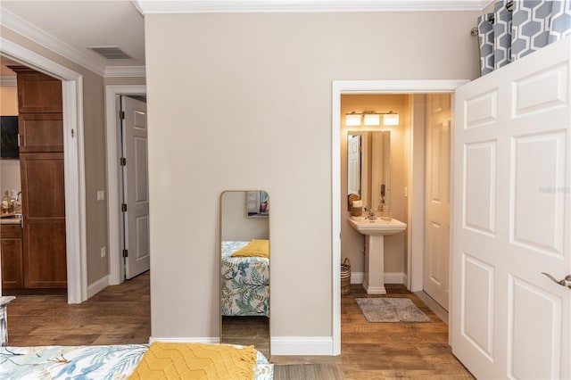 bedroom with baseboards, visible vents, wood finished floors, ensuite bathroom, and crown molding