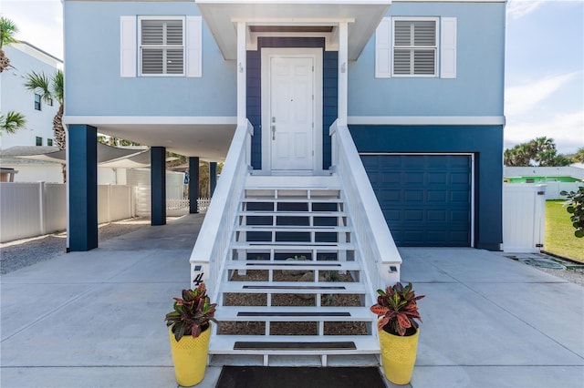 doorway to property featuring a garage, concrete driveway, a carport, and stucco siding