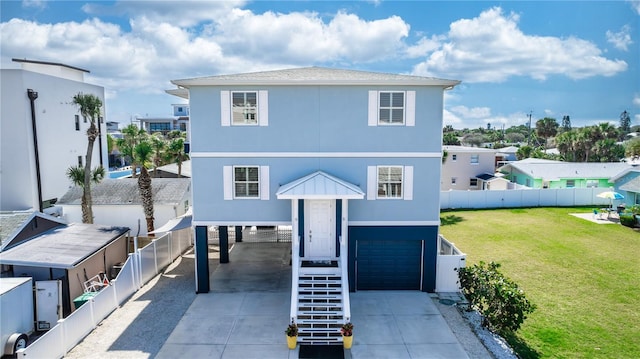 coastal home featuring concrete driveway, an attached garage, stairs, fence, and a front yard