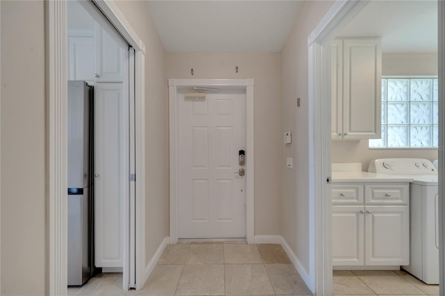 interior space featuring light tile patterned floors, baseboards, and washer / dryer