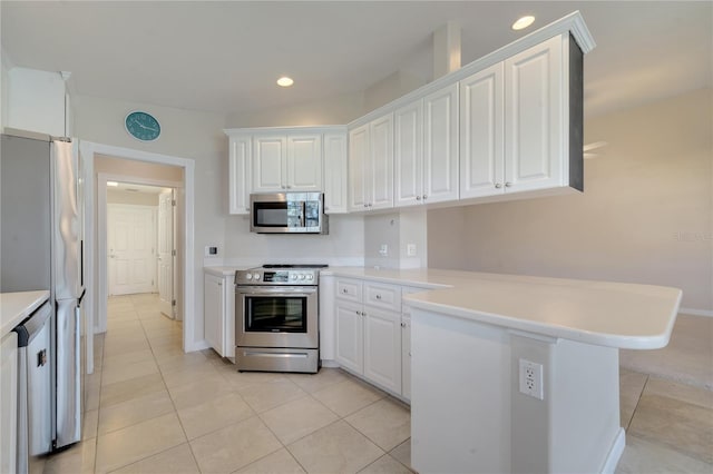 kitchen with white cabinets, appliances with stainless steel finishes, and a peninsula