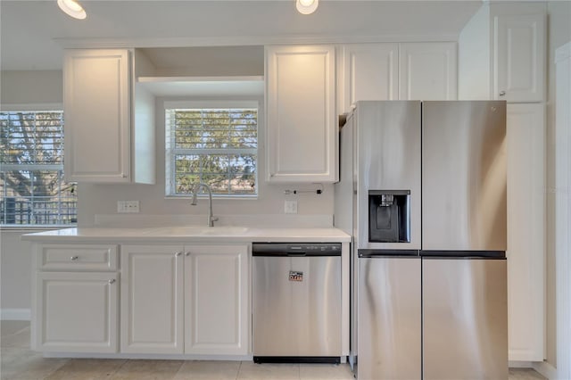 kitchen featuring white cabinets, stainless steel appliances, light countertops, and a sink