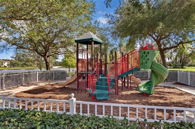 community jungle gym with a water view and fence