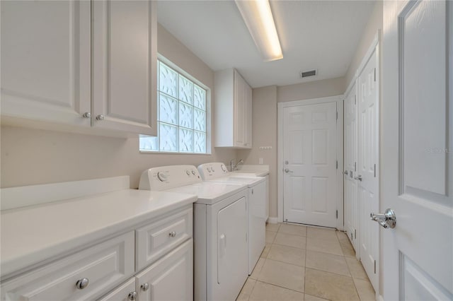 clothes washing area with separate washer and dryer, light tile patterned floors, cabinet space, and visible vents