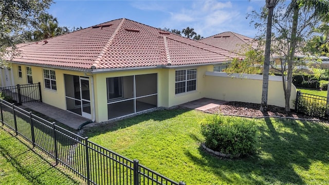 rear view of house featuring a tiled roof, a fenced backyard, a lawn, and stucco siding