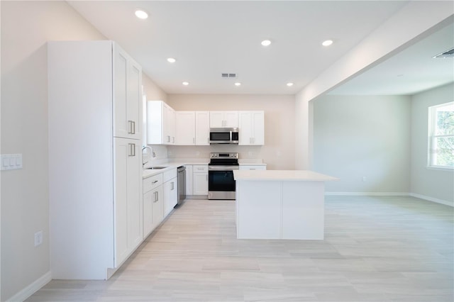 kitchen featuring sink, light wood-type flooring, a kitchen island, stainless steel appliances, and white cabinets