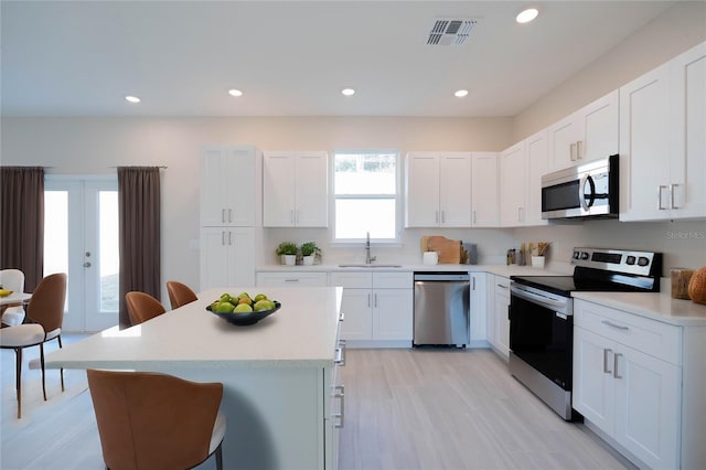 kitchen featuring white cabinetry, sink, a kitchen bar, a center island, and stainless steel appliances