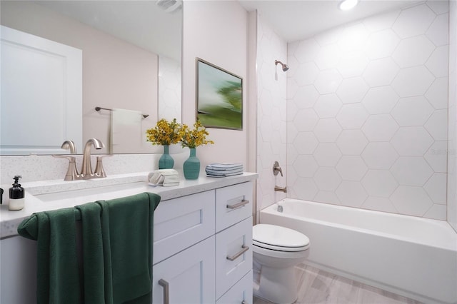 full bathroom with tiled shower / bath, vanity, and toilet