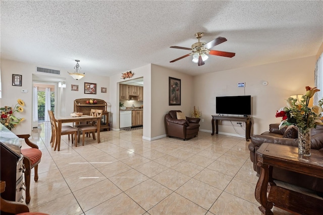 living room featuring light tile patterned floors, visible vents, baseboards, a ceiling fan, and a textured ceiling