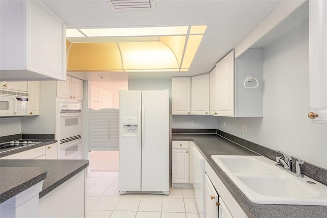 kitchen with sink, white appliances, light tile patterned floors, and white cabinets