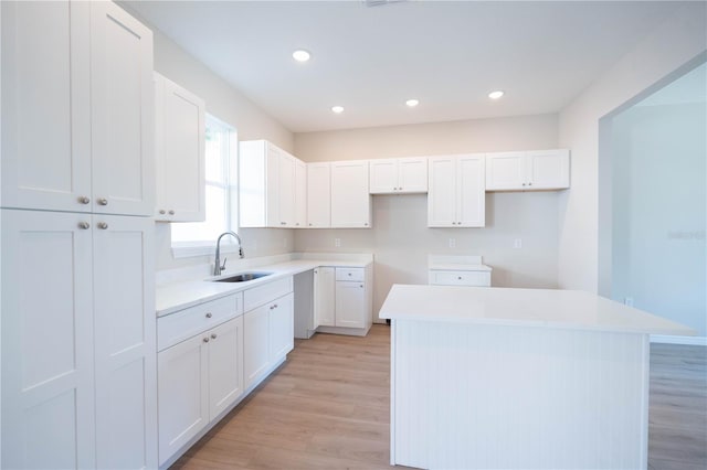 kitchen with a kitchen island, sink, white cabinets, and light wood-type flooring