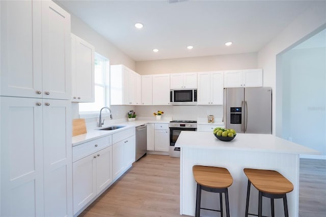 kitchen featuring stainless steel appliances, sink, white cabinets, and a breakfast bar