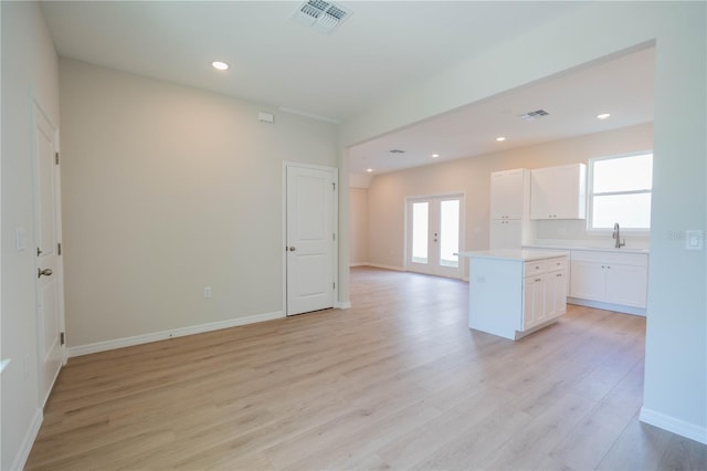 kitchen with white cabinetry, light hardwood / wood-style floors, a kitchen island, and french doors