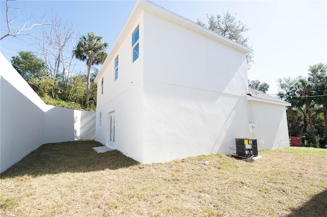 rear view of property featuring a lawn and central air condition unit