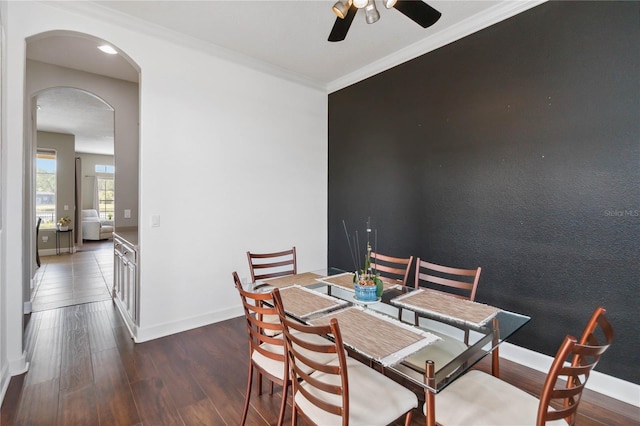 dining area with dark wood-type flooring, ceiling fan, and crown molding