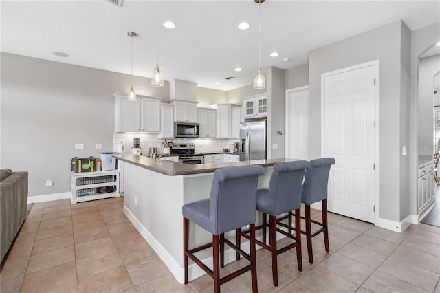 kitchen with hanging light fixtures, tasteful backsplash, appliances with stainless steel finishes, and white cabinets