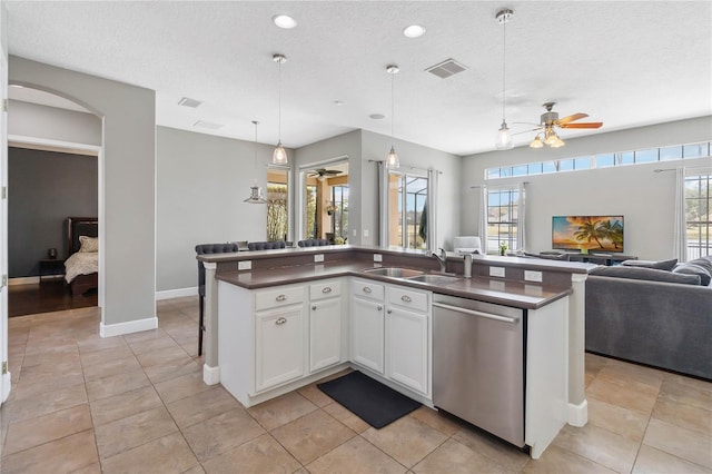 kitchen with decorative light fixtures, dishwasher, sink, white cabinets, and a center island with sink