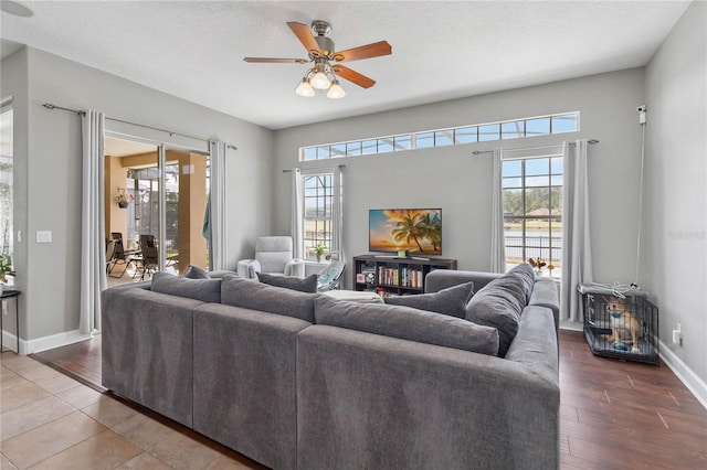 living room with dark wood-type flooring, ceiling fan, plenty of natural light, and a textured ceiling