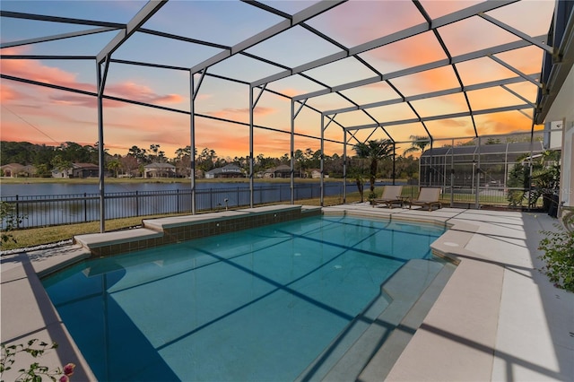 pool at dusk featuring a patio, a water view, and glass enclosure