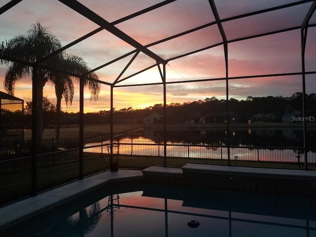 pool at dusk with a lanai, a patio, and a water view