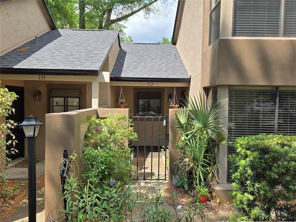 940 Douglas Ave Unit 132, Altamonte Springs, FL 32714 - view of exterior entry featuring stucco siding, roof with shingles, and a gate