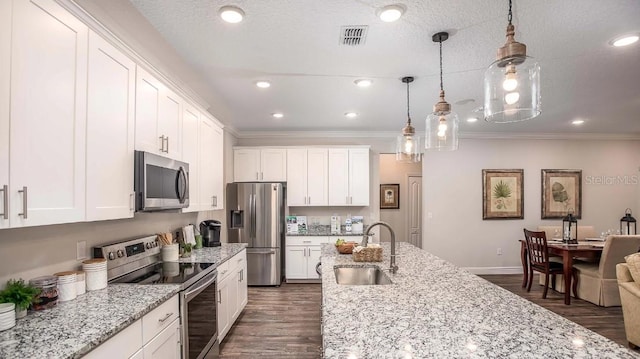 kitchen featuring pendant lighting, sink, stainless steel appliances, and white cabinets