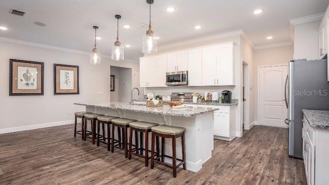 kitchen with stainless steel appliances, hanging light fixtures, a kitchen island with sink, and white cabinets