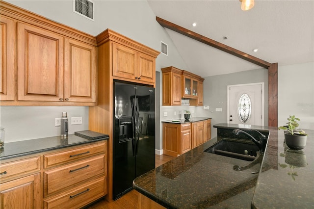 kitchen with sink, vaulted ceiling with beams, wood-type flooring, black refrigerator with ice dispenser, and dark stone counters