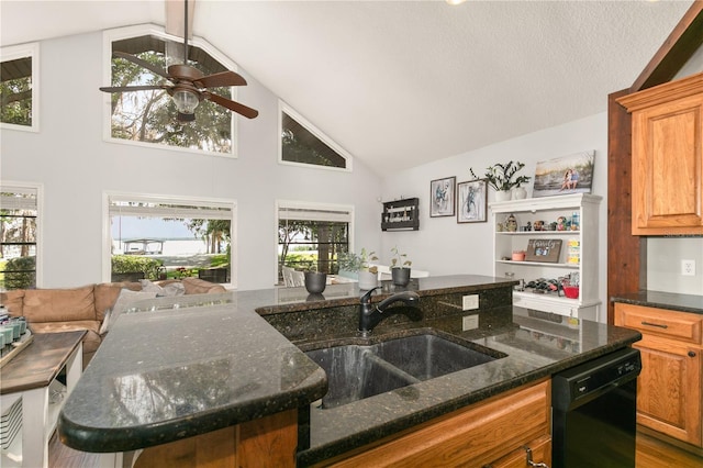 kitchen with sink, a breakfast bar, dishwasher, dark stone countertops, and a kitchen island