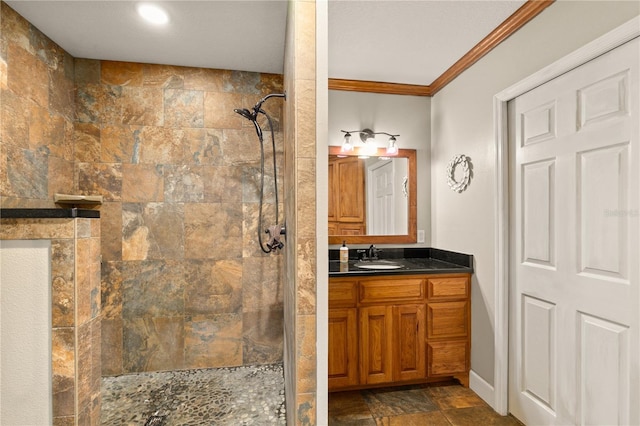 bathroom featuring vanity, a tile shower, and crown molding