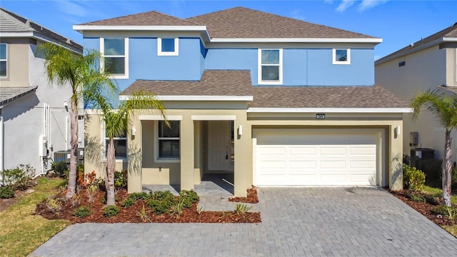 view of front of home featuring a garage, a shingled roof, central AC unit, decorative driveway, and stucco siding