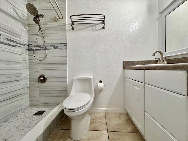 bathroom featuring a tile shower, vanity, tile patterned flooring, and toilet