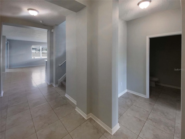 corridor featuring light tile patterned floors and a textured ceiling