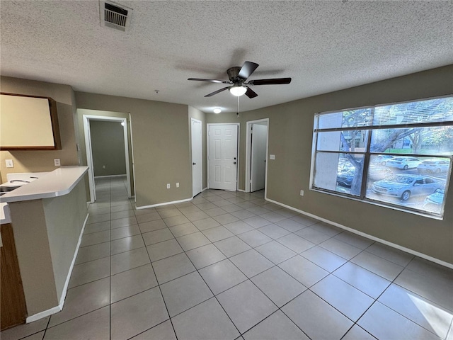 unfurnished living room featuring light tile patterned flooring, a textured ceiling, and ceiling fan