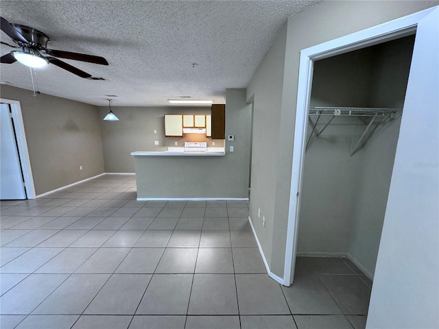 kitchen with tile patterned floors, decorative light fixtures, a textured ceiling, kitchen peninsula, and ceiling fan