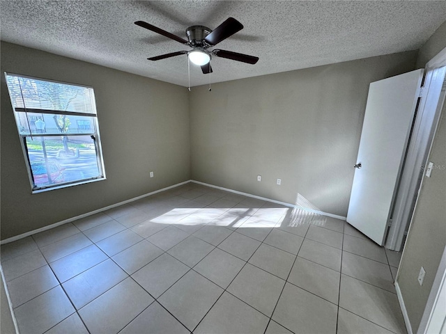 spare room with light tile patterned flooring, ceiling fan, and a textured ceiling