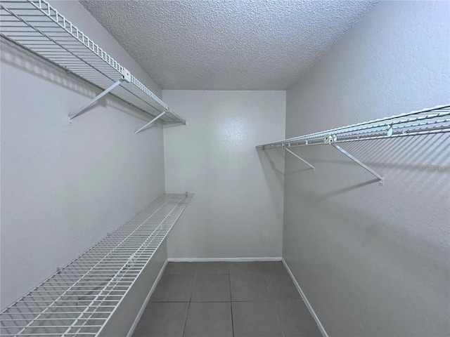 walk in closet with dark tile patterned floors