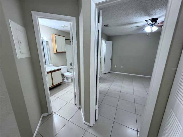 hall with light tile patterned flooring, electric panel, and a textured ceiling