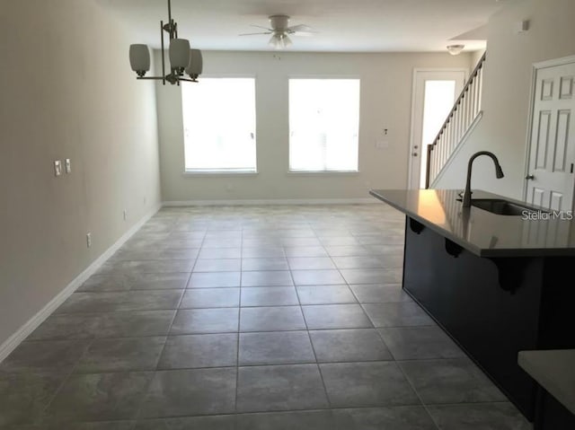 kitchen featuring sink, a breakfast bar, dark tile patterned floors, ceiling fan, and decorative light fixtures